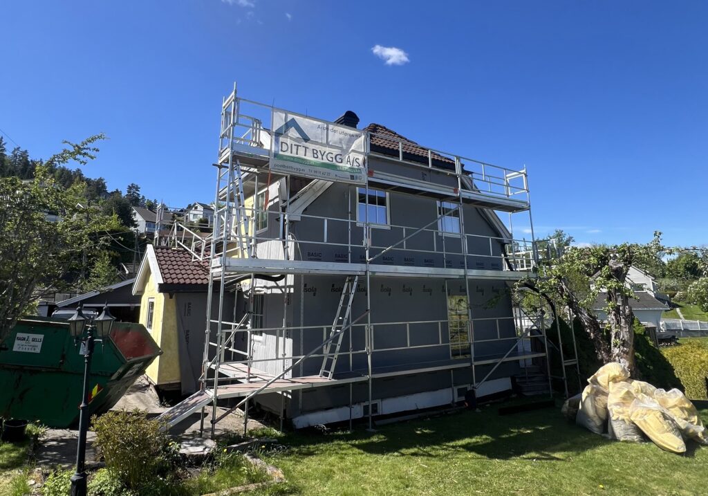 Grått hus med stillas festet rundt veggene.