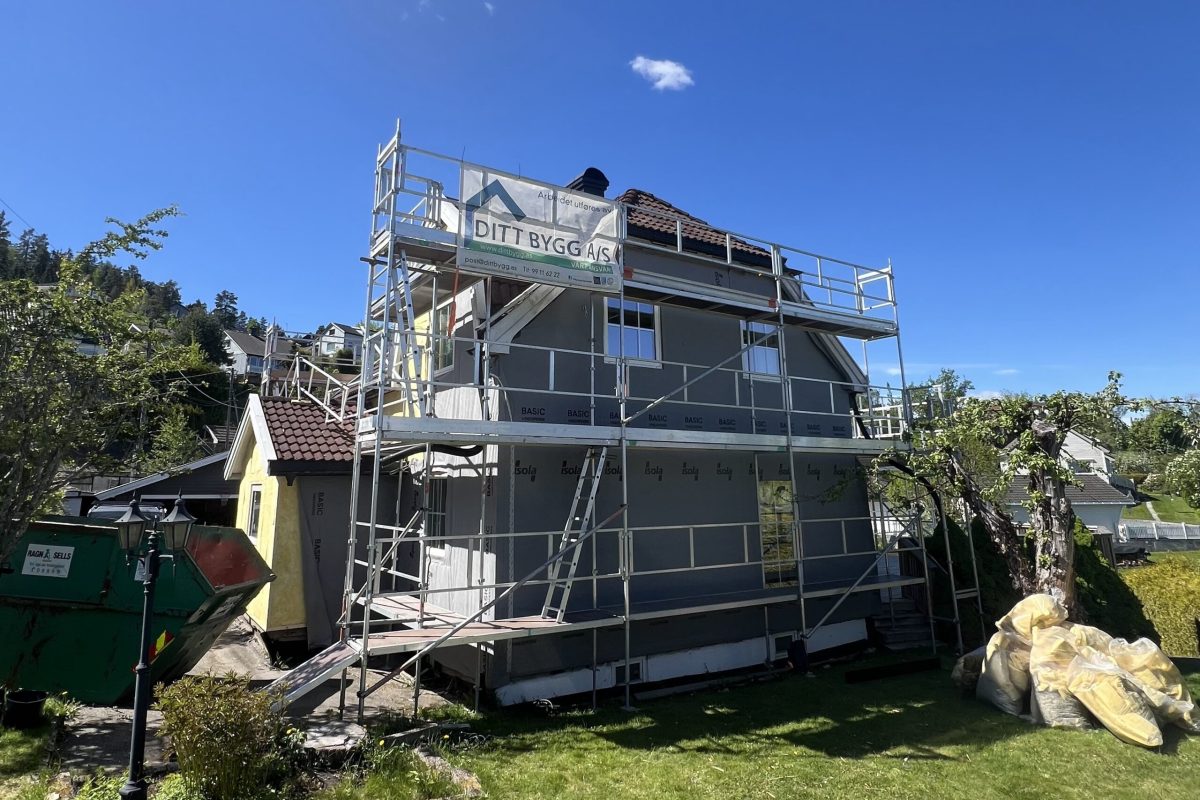 Grått hus med stillas festet rundt veggene.